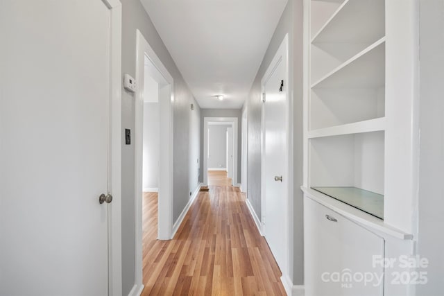 corridor featuring light wood-type flooring and baseboards