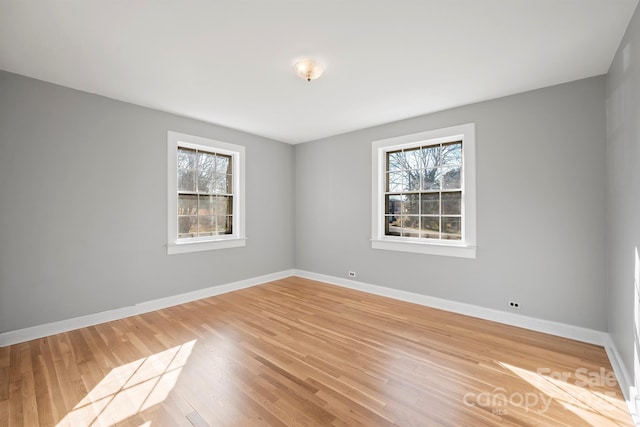 spare room with a healthy amount of sunlight, baseboards, and light wood-type flooring