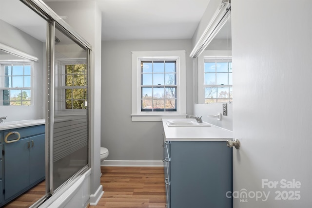 bathroom featuring vanity, toilet, wood finished floors, and baseboards