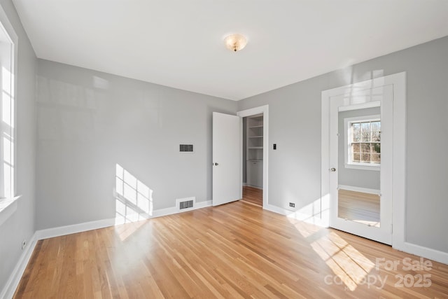 unfurnished room with visible vents, light wood-style flooring, and baseboards