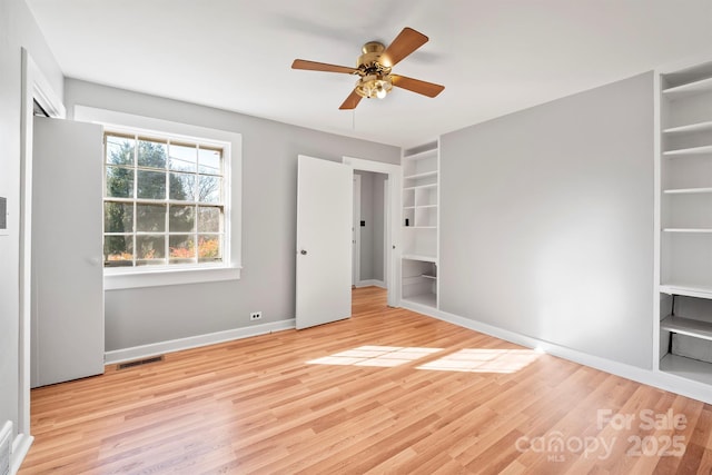 unfurnished bedroom with a ceiling fan, wood finished floors, visible vents, and baseboards