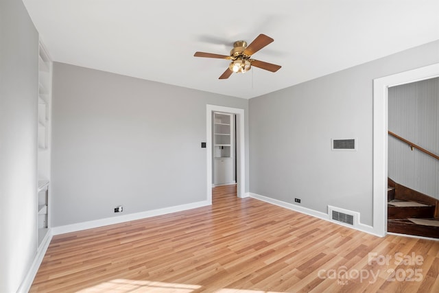 empty room featuring stairway, light wood-style flooring, and visible vents