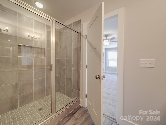 bathroom featuring wood-type flooring, a shower with door, and ceiling fan