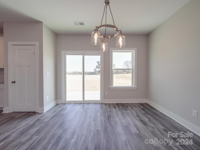 unfurnished dining area with a chandelier and dark wood-type flooring