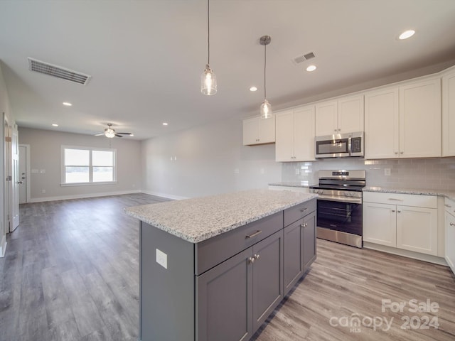 kitchen with light hardwood / wood-style flooring, tasteful backsplash, stainless steel appliances, and white cabinetry