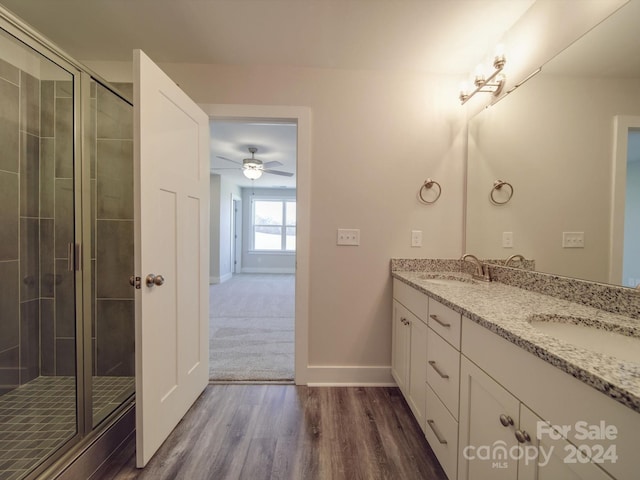 bathroom with a shower with shower door, ceiling fan, hardwood / wood-style floors, and dual vanity