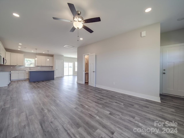 unfurnished living room with ceiling fan and dark wood-type flooring