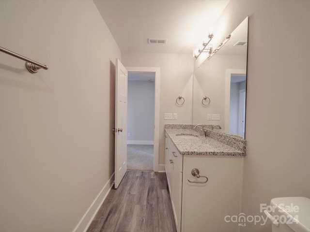 bathroom with wood-type flooring, toilet, and large vanity