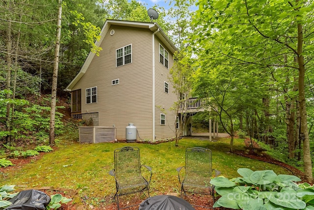 view of side of home with a deck and a lawn