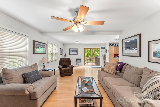 living room with heating unit, a wealth of natural light, ceiling fan, and light wood-type flooring