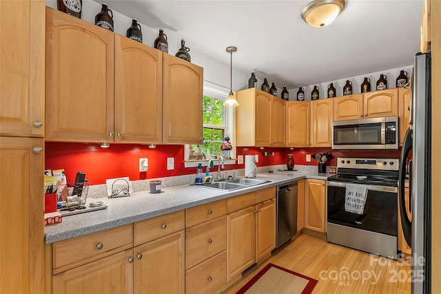 kitchen featuring sink, hanging light fixtures, light wood-type flooring, stainless steel appliances, and light stone countertops