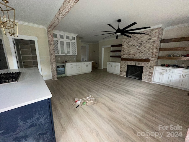 unfurnished living room with a textured ceiling, a brick fireplace, ornamental molding, and beverage cooler