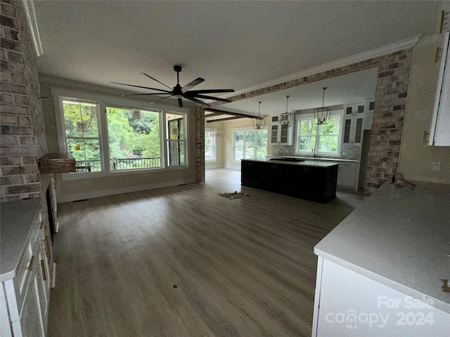 unfurnished living room with brick wall, ornamental molding, and a healthy amount of sunlight