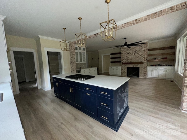 kitchen with a center island, decorative light fixtures, light wood-type flooring, a brick fireplace, and blue cabinets