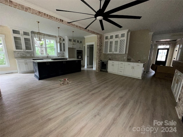 kitchen with beverage cooler, white cabinets, a center island, decorative light fixtures, and decorative backsplash