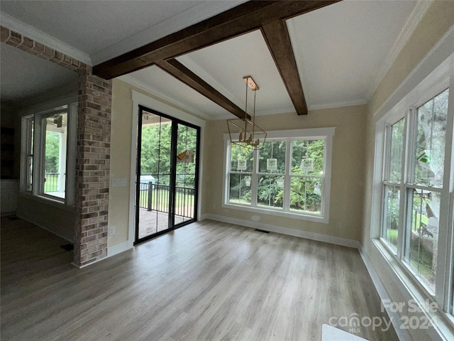 unfurnished dining area featuring plenty of natural light, ornamental molding, beamed ceiling, and light wood-type flooring