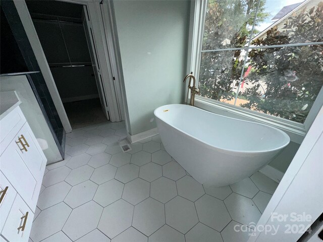 bathroom featuring vanity, tile patterned floors, and a washtub