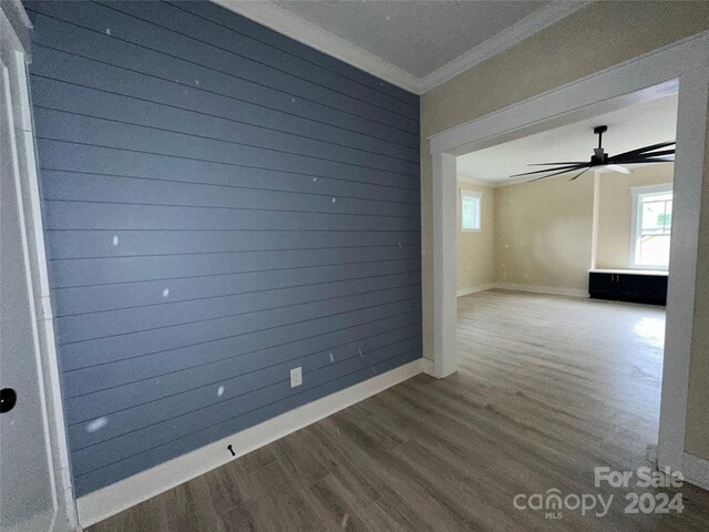 unfurnished room featuring hardwood / wood-style flooring, plenty of natural light, wood walls, and crown molding