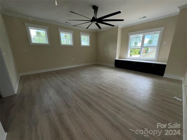 empty room featuring a healthy amount of sunlight, wood-type flooring, and crown molding