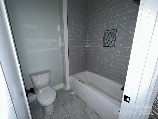 bathroom featuring toilet and tiled shower / bath