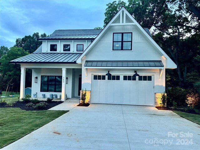 modern farmhouse style home featuring a front yard, a garage, and a porch