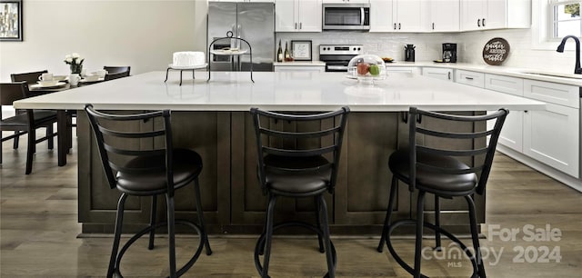 kitchen with white cabinetry, sink, appliances with stainless steel finishes, a kitchen breakfast bar, and a kitchen island