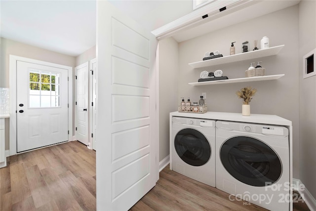 clothes washing area with washing machine and dryer and light hardwood / wood-style floors