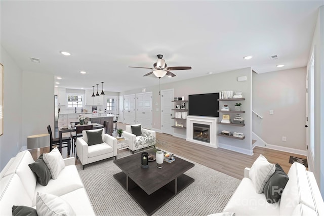 living room featuring ceiling fan and light hardwood / wood-style flooring