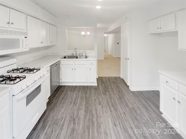 kitchen featuring white cabinets, sink, white appliances, light hardwood / wood-style floors, and an inviting chandelier