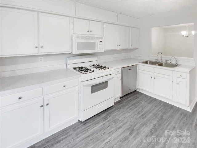 kitchen with sink, white appliances, white cabinets, hardwood / wood-style floors, and a chandelier