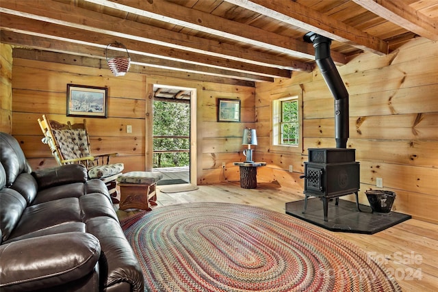 living room with beam ceiling, wood ceiling, a wood stove, wood walls, and hardwood / wood-style flooring