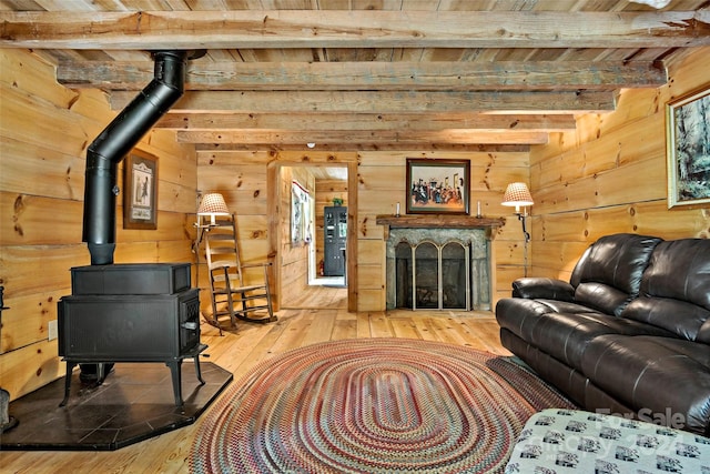 living room with beamed ceiling, wood ceiling, a wood stove, and hardwood / wood-style floors