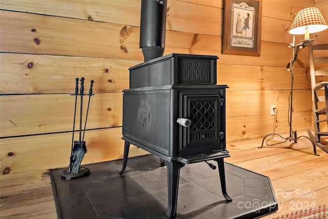 details featuring wooden walls, a wood stove, and hardwood / wood-style floors