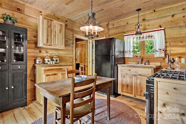 kitchen featuring light hardwood / wood-style floors, wood walls, wooden ceiling, gas stove, and black refrigerator