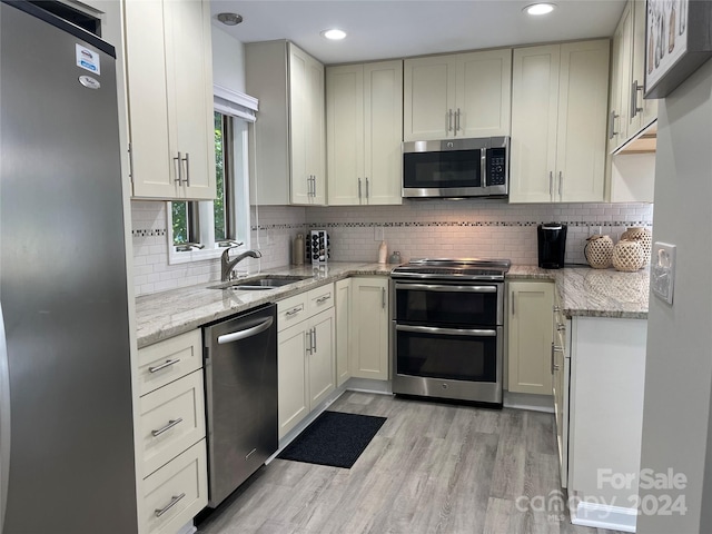 kitchen featuring light hardwood / wood-style flooring, sink, stainless steel appliances, and light stone countertops