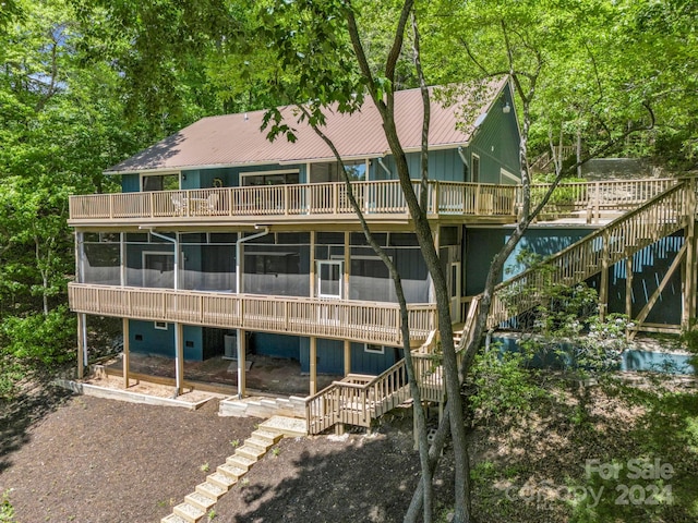 rear view of property with a deck and a sunroom