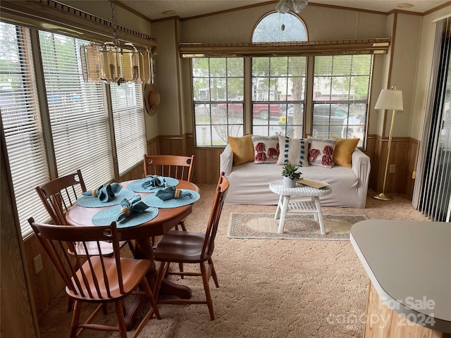 dining room with ornamental molding, carpet flooring, lofted ceiling, and an inviting chandelier