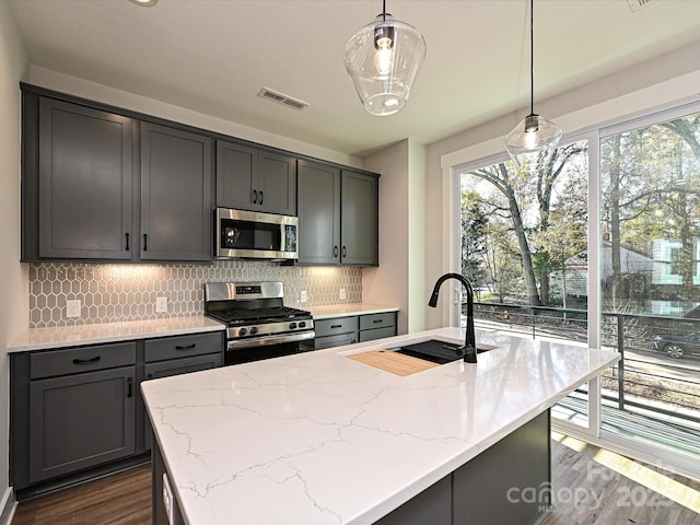 kitchen featuring stainless steel appliances, pendant lighting, visible vents, and a sink