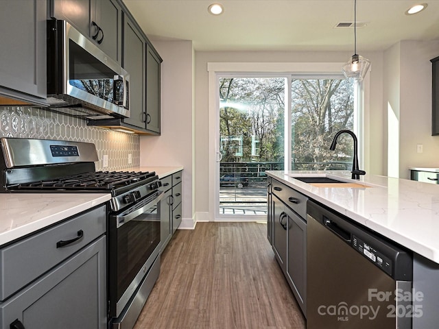 kitchen featuring pendant lighting, tasteful backsplash, visible vents, appliances with stainless steel finishes, and a sink