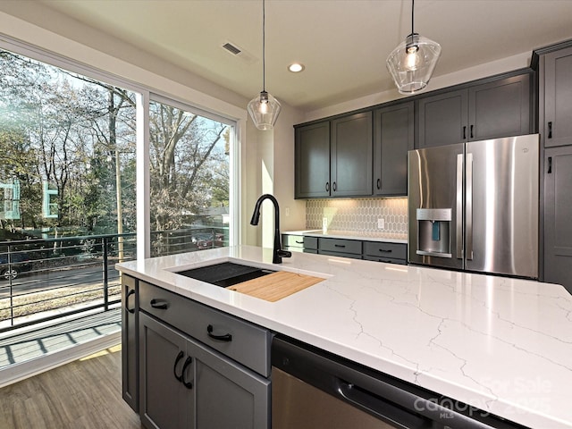 kitchen with pendant lighting, visible vents, light stone countertops, and stainless steel fridge with ice dispenser