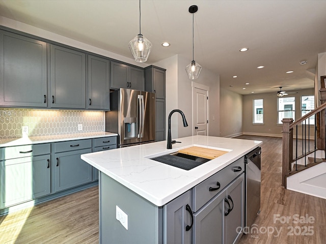 kitchen featuring a center island with sink, open floor plan, decorative light fixtures, stainless steel appliances, and a sink