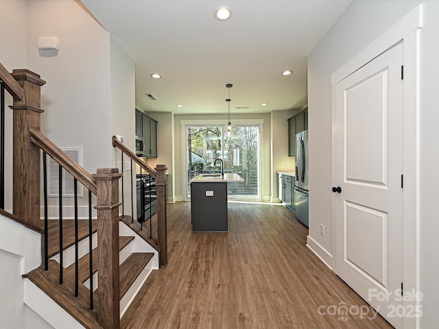 interior space featuring dark wood finished floors, appliances with stainless steel finishes, decorative light fixtures, light countertops, and a sink