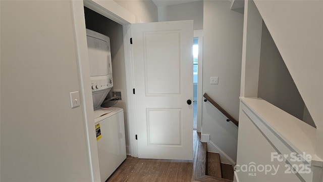 laundry area featuring laundry area, stacked washer / dryer, and dark wood-style flooring