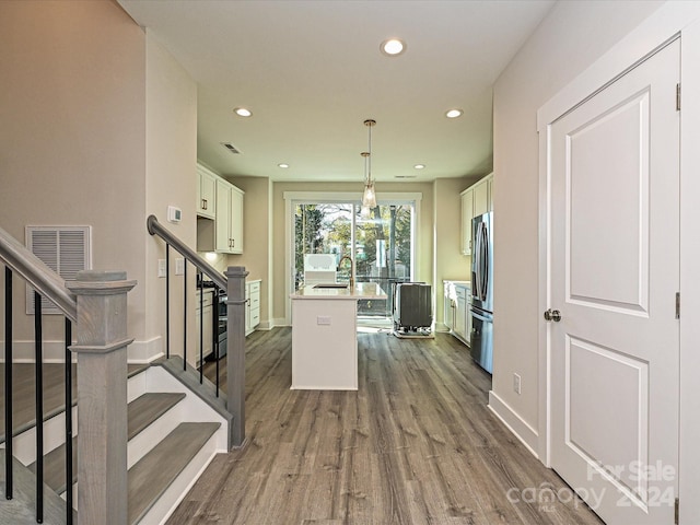 kitchen featuring stainless steel refrigerator, white cabinetry, sink, dark hardwood / wood-style flooring, and pendant lighting