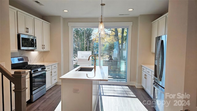 kitchen featuring sink, hanging light fixtures, an island with sink, white cabinets, and appliances with stainless steel finishes