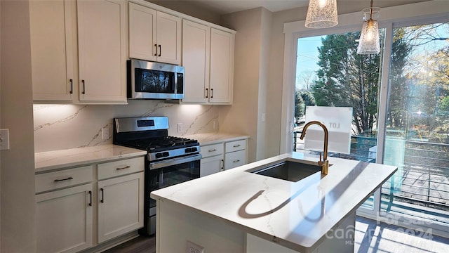 kitchen with backsplash, sink, hanging light fixtures, an island with sink, and stainless steel appliances