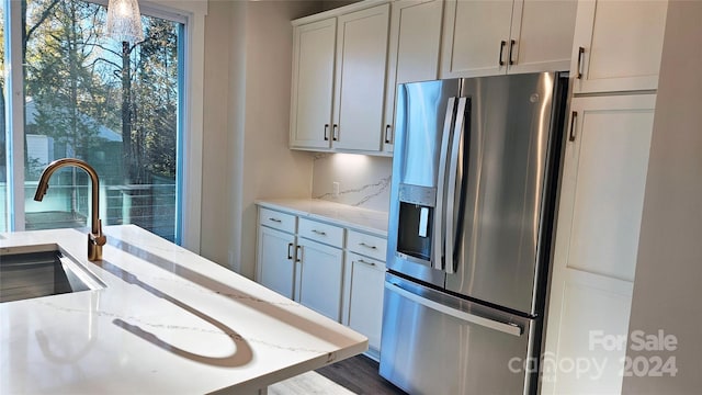 kitchen featuring white cabinets, sink, stainless steel fridge, light stone counters, and dark hardwood / wood-style flooring