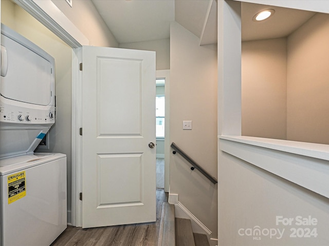 laundry room with dark hardwood / wood-style flooring and stacked washer and clothes dryer