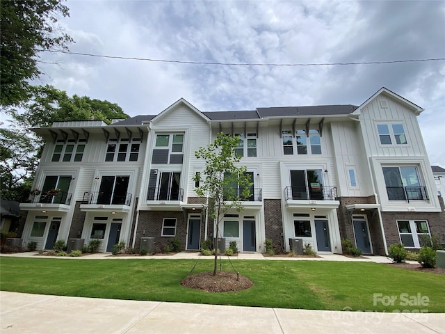 1217 E 34th St Unit Csw0316, Charlotte, NC 28205 - view of property featuring board and batten siding, a front lawn, brick siding, and a balcony
