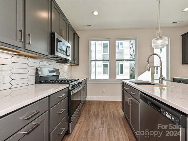 kitchen with pendant lighting, sink, dark hardwood / wood-style floors, light stone countertops, and appliances with stainless steel finishes